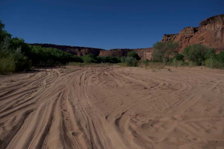 The sandy canyon floor covered in car and horse tracks